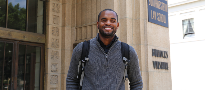 Student smiling in front of Southwestern Law School sign