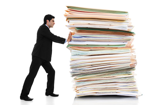 student pushing a gigantic stack of books and papers