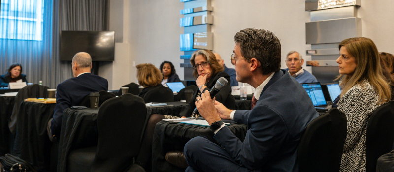 Professor Jolly speaking on a mic in the audience at a conference