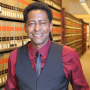 Image - Prof Kevin J Greene in red shirt and gray vest and gray tie standing in library aisle