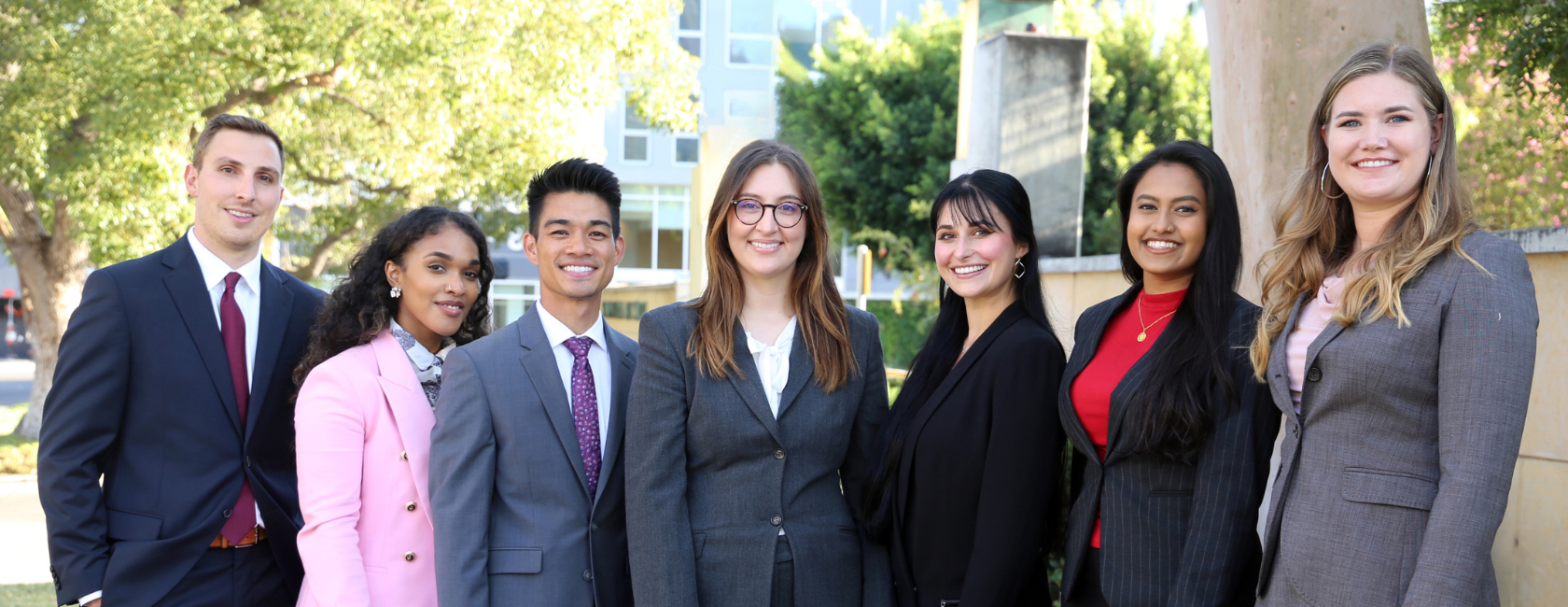 Seven Southwestern students smiling at camera in business formal dress