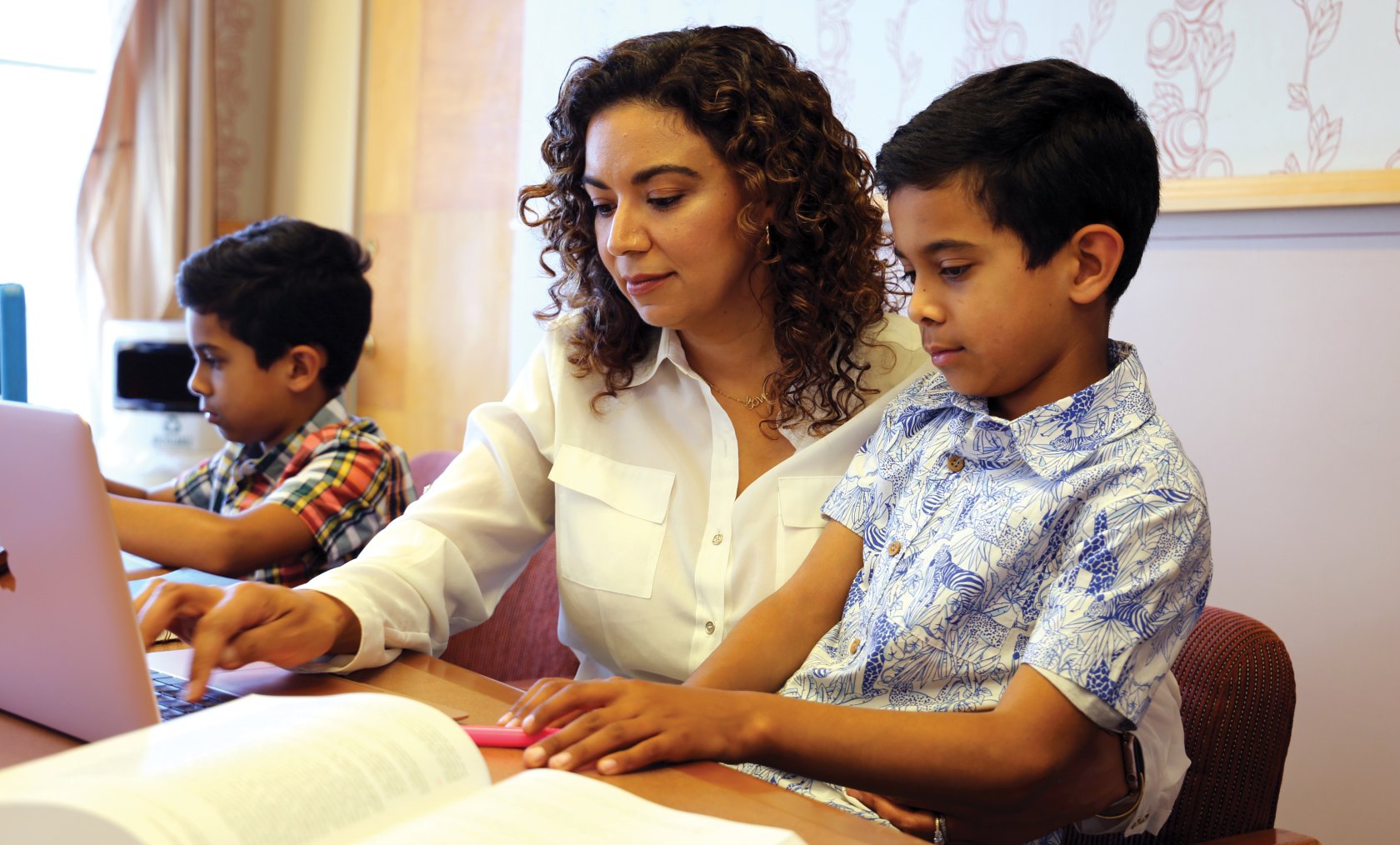 Southwestern student with her children working on her laptop