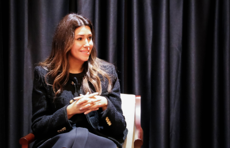 Camille Vasquez '10 sitting at speaking event in front of black curtains